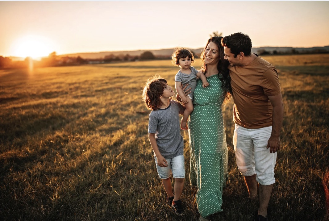 Familia hispana caminando juntos al atardecer en el campo